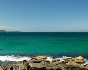Fototapeta na wymiar Rocks on the beach with horizon in the background - Manly Beach, Sydney, Australia