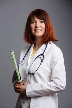 Image of young female doctor with phonendoscope and folder in hands