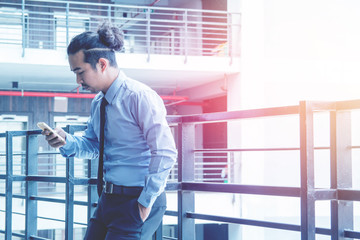 Asian young businessman holding mobile phone chat Meetings the commercial processes involved in...