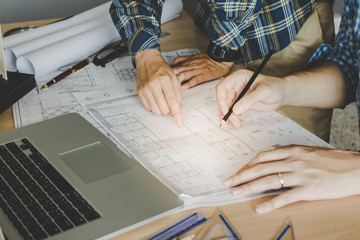 Concept architects,engineer holding pen pointing equipment architects On the desk with a blueprint in the office, Vintage, Sunset ligth.Selective Focus
