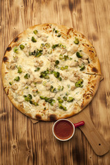 Pizza with chicken and broccoli on wooden board served with ketchup