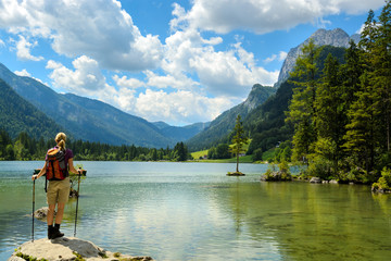 Young hiker woman standing by alpine lake watching mountain landscape. Hintersee, Germany