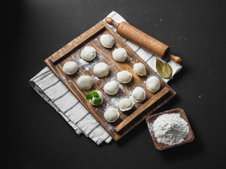 Frozen raw dumplings on the wooden desk on black background
