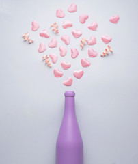 Splashing hard with love / Creative concept photo of champagne bottle splashing with hearts and love on grey background.