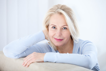 Active beautiful middle-aged woman smiling friendly and looking in camera. Woman's face closeup. Realistic images without retouching with their own imperfections. Selective focus. - obrazy, fototapety, plakaty