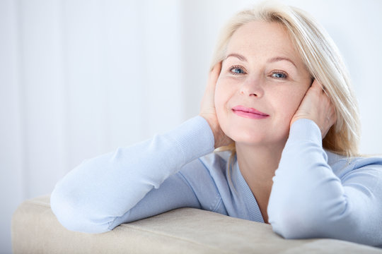 Active beautiful middle-aged woman smiling friendly and looking in camera. Woman's face closeup. Realistic images without retouching with their own imperfections. Selective focus.