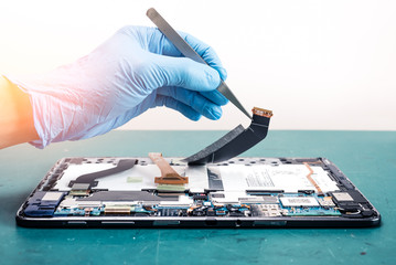 The asian technician repairing the tablet's motherboard in the lab. the concept of computer...