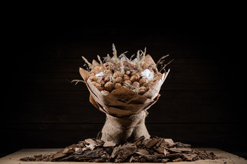 Bouquet of brown nuts on wood background in a paper wrapper