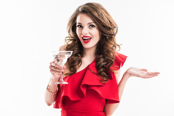 surprised fashionable girl in red dress holding glass of cocktail isolated on white