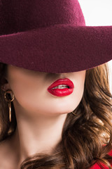 sexy woman with red lips hiding eyes under burgundy hat