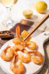 Fried shrimps with chopsticks on a white wooden board