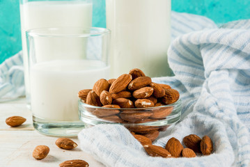 Vegan alternative food, almond non-dairy milk on light blue background, copy space