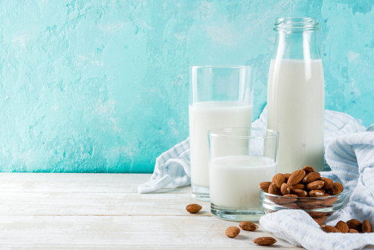 Vegan alternative food, almond non-dairy milk on light blue background, copy space