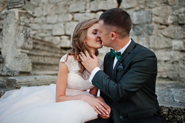Romantic wedding couple sitting on the stairs next to the castle.