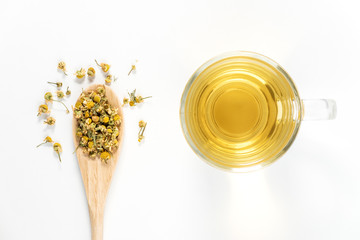 Dry Camomile Tea in a spoon on white background.