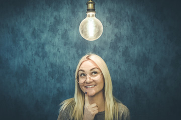 Smiling beautiful woman having an idea with light bulb over her head