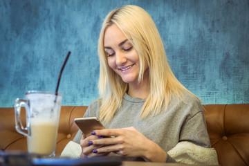 Portrait of young female using smart phone in coffeehouse