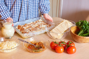 The housewife cooks meat lasagna in the kitchen. homemade food