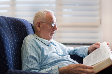 Old man reading book at home