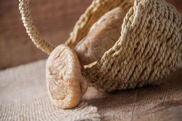 figues séchées tombant d'un petit panier en osier sur fond en bois et toile de jutte