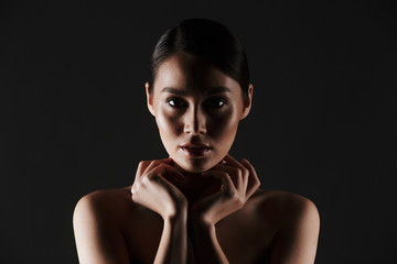 Obraz premium Beauty portrait of sexual caucasian woman with brown hair in bun posing at camera with beautiful look, isolated over black background