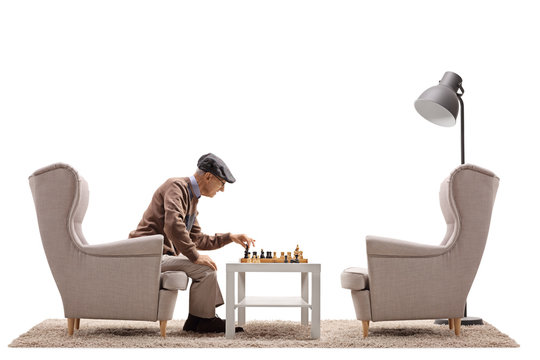 Senior seated in an armchair playing chess by himself
