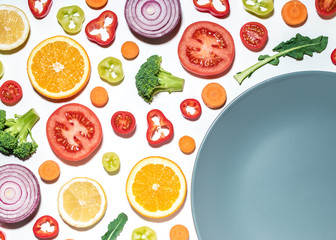 Creative layout of sliced vegetables and fruits with plate on white background.  Flat lay. Food vegan concept.