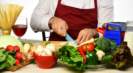 Cook burgundy uniform cuts vegetables. Chef prepares meal.
