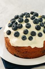 Sour cream and blueberry cake served on a plate on a white stone background