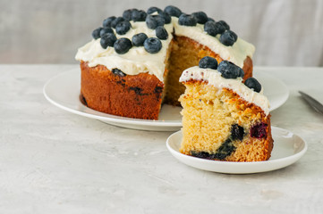 Sour cream and blueberry cake served on a plate on a white stone background
