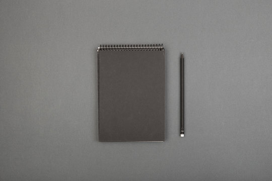 Top view of open spiral blank notebook with pencil on gray background