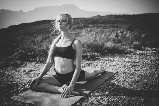 Female model practicing yoga in the outdoors doing stretching and exercising balance.
