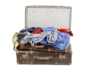 Old suitcase full of clothes isolated on white background