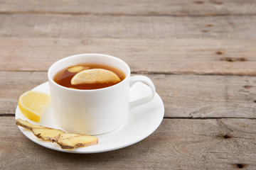 Ginger tea in a cup on wooden background