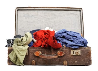 Old suitcase full of clothes isolated on white background