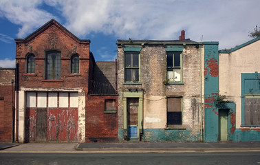 derelict houses and abandone garage on a residential street with boarded up windows and decaying crumbling walls