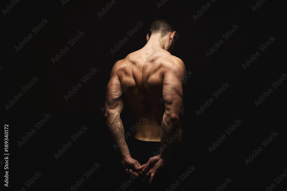 Wall mural Unrecognizable man shows strong back muscles closeup