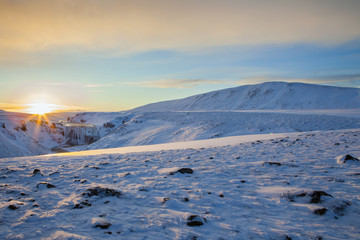 Sunrise over frozen waterfall in Iceland