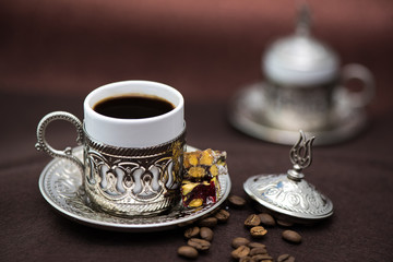 Traditional Turkish coffee in traditional metal cup on brown background