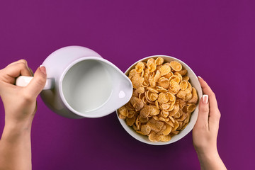 Food and people concept - hands of woman eating cereals corn flakes for breakfast and pouring milk