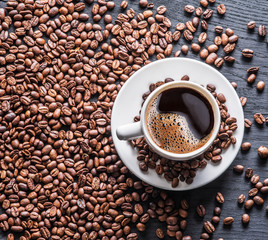 Cup of coffee surrounded by coffee beans. Top view.
