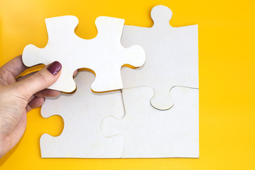 Fototapeta premium woman hand and four puzzles on yellow background