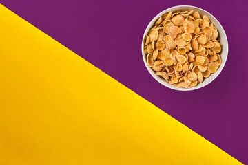 Bowl with cornflakes on the colorful background