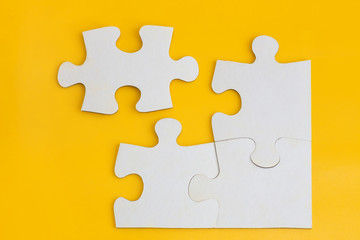 Obraz premium Four disconnected jigsaw puzzle pieces on yellow background. Concept of finding right solutions in teamwork.