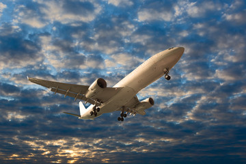 The passenger plane in flight. Aircraft climb into the sunset cloudy sky. Airplane bottom view.