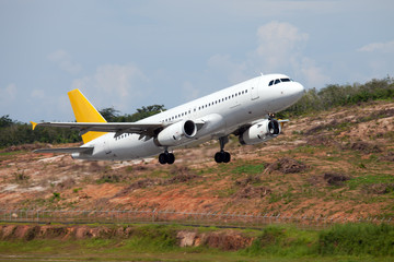 Passenger aircraft is climbing into the sky. Green hills on the aircraft background.