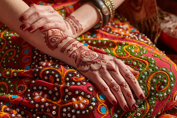 Mehendi on his hands against the backdrop of a national Indian costume. Close-up.