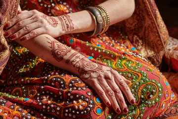 Mehendi on his hands against the backdrop of a national Indian costume. Close-up.