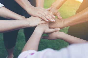 Obraz na płótnie Canvas Closeup of stack of hands. Colleague putting their hands on top of each other symbolizing unity and teamwork while doing activity outdoor. People joining hand together as a business goal achievement.