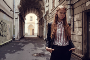 Fototapeta na wymiar A young red-haired girl in a business suit is walking along a beautiful old town. St.Petersburg